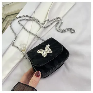 Close-up of black wrinkled texture mini bag with silver bow buckle and chain strap