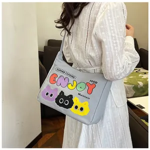 Borsa a tracolla in tela con gatti e scritta ENJOY indossata su abito in pizzo