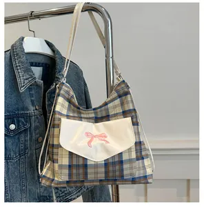 Detail view of a plaid tote bag with a pink bow pocket, styled with a denim jacket