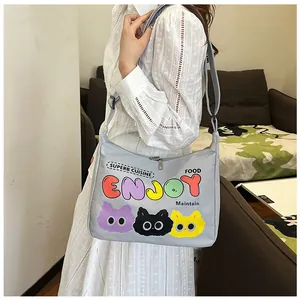 Dettaglio borsa in tela grigio chiaro con gatti cartoon e tracolla su un abito bianco