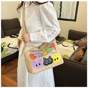 Dettaglio borsa a tracolla in tela beige con tre stampe colorate di gatti cartoon