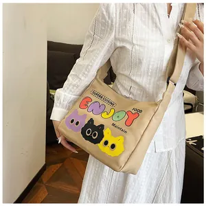 Dettaglio borsa a tracolla in tela kaki con stampe di gatti cartoon e tracolla regolabile