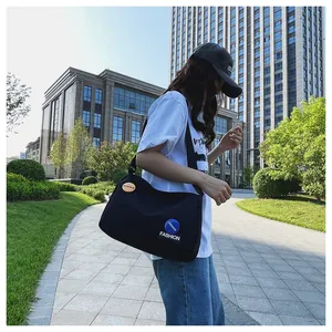 Detalle de bolso bandolera de lona negra con parches de moda en un entorno urbano