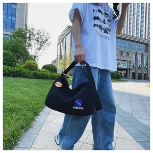 Detalle de bolso hobo de lona negra con insignias de moda y correa ancha ajustable