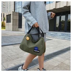 Vista detallada del bolso de lona verde oscuro con asas negras y parches decorativos de moda