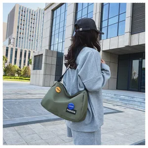 Vista lateral exterior de bolso bandolera de lona verde oliva con parches de moda