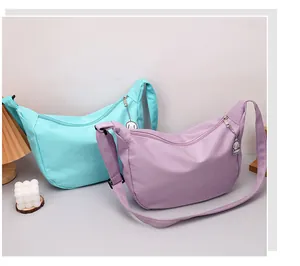 Detail of waffle textured crossbody bag with metal charm and adjustable fabric strap