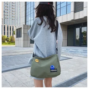 Vista posterior detallada de un bolso bandolera de lona verde militar con parches de moda