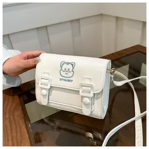 Close-up of white PU leather crossbody bag featuring blue cartoon embroidery and straps