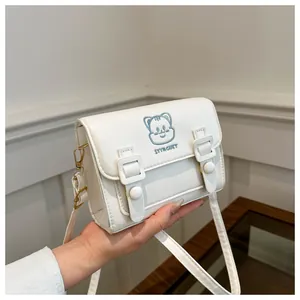Detail of cute cat embroidery and decorative buckles on a white PU leather crossbody bag