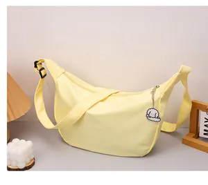 Detail of light yellow waffle crescent bag with cute white puppy pendant accessory