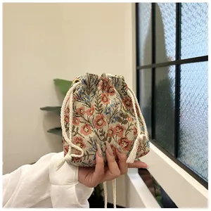 Detail of floral jacquard bucket bag with cotton drawstring and tassel trim accents