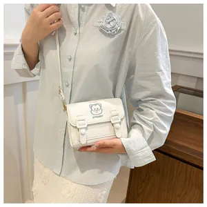 Detail of white PU leather crossbody bag featuring cartoon cat embroidery and buckles