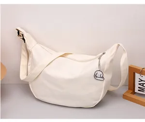 Detail of off-white crescent crossbody bag with adjustable strap and cute puppy pendant