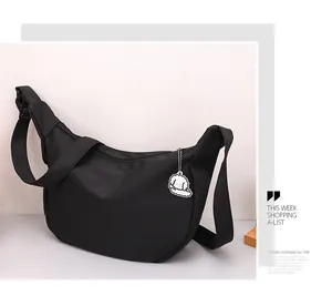 Detail of a black waffle crossbody dumpling bag with a cute white puppy plush charm