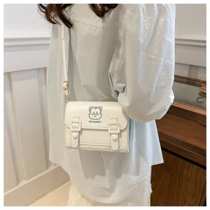 Detail of white PU leather crossbody bag featuring a cute blue cartoon bear embroidery