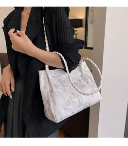 Detailed side view of white tote bag with butterfly prints and braided rope handles