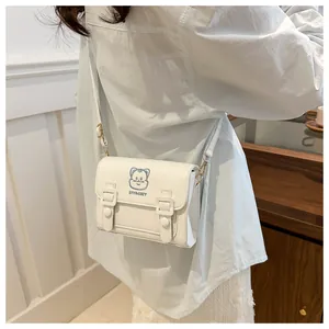 Detail of a creamy white PU leather crossbody bag featuring a blue cat cartoon graphic