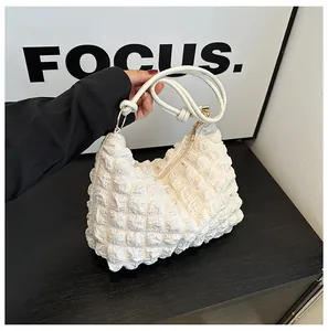 Close-up of white popcorn pleat texture and metallic ring detail on shoulder bag