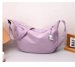Detail of purple waffle fabric crescent bag with an adjustable strap and cute dog charm