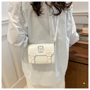 Detail of white PU leather crossbody bag with blue cat embroidery and flap closure