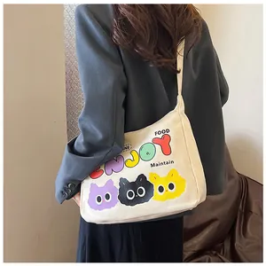 Dettaglio di una grande borsa a spalla in tela bianco crema con stampe di gatti su modella