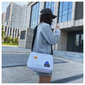 Foto exterior del bolso bandolera de lona blanca con correa ajustable y parches de moda