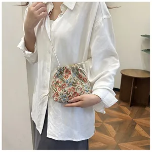 Detail of vintage floral drawstring bucket bag worn by a model in a casual setting