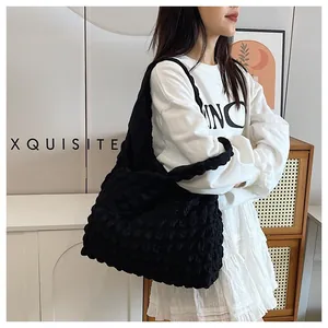 Detail of black pleated hobo bag with unique bubble texture and wide shoulder strap