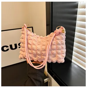 Detail of pink pleated puff shoulder bag showing soft bubble texture and metallic rings