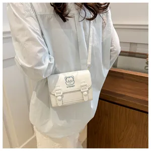 Close-up of white PU leather crossbody bag featuring cartoon cat embroidery and buckles
