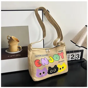 Dettaglio borsa a tracolla in tela con lettere ENJOY colorate e stampe di gatti cartoni