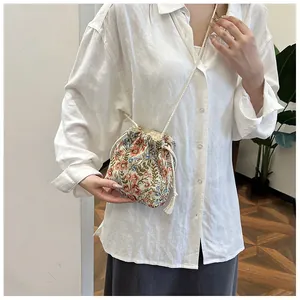Close-up of small floral drawstring bucket bag with cotton rope strap in daily use