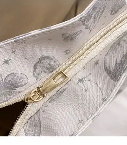 Detailed close-up of golden metal zipper and printed canvas fabric on a tote bag