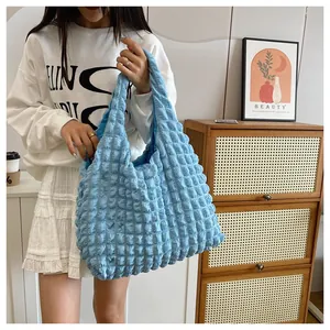 Detail of light blue pleated tote bag with unique bubble texture held by a female model