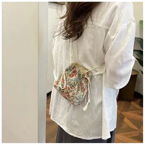 Close-up of floral embroidery detail on a beige drawstring bucket crossbody bag