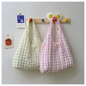 Close-up of popcorn texture fabric on cream and pink striped tote bags on a hanger