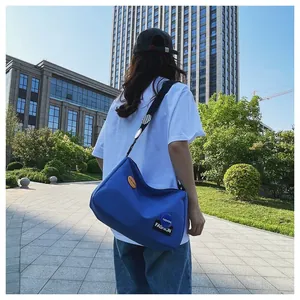 Vista trasera exterior de un gran bolso bandolera de lona azul real con correa ajustable