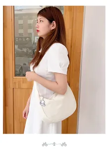 Close-up of white waffle texture crossbody crescent bag with cute dog pendant