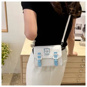 Close-up of a white PU crossbody bag with blue cartoon embroidery and straps