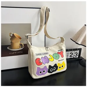 Dettaglio borsa in tela beige con stampe di gatti e cerniera su tavolo in legno