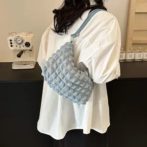 Chic light blue pleated shoulder bag with bubble texture shown on a female model