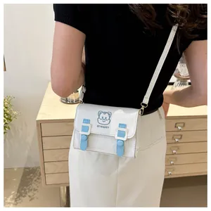 Lifestyle shot of an off-white PU leather crossbody bag with blue cat embroidery on the flap