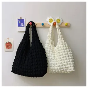 Detail of bubble textured knit handbags in black and cream white on wooden hooks