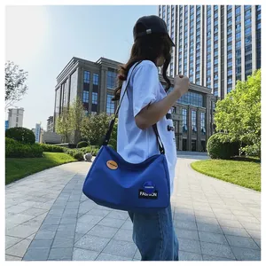 Foto exterior de un bolso bandolera de lona azul con detalle de correa ajustable