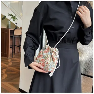 Detail of floral drawstring bucket bag showing vintage patterns and woven rope strap