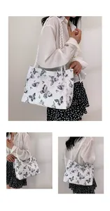 Detail of white tote bag with black butterfly prints and woven rope shoulder straps