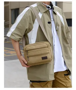 Detail of khaki canvas crossbody bag showing three functional zipper pockets and Sport label