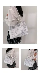 Medium white tote bag with gray butterfly print and woven straps worn by model