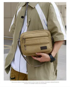 Detailed view of khaki canvas crossbody bag with multiple zipper layers and sport label